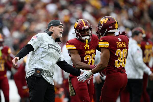 Washington Commanders head coach Dan Quinn reaches out to running back Austin Ekeler (30) after his touchdown during the first half of an NFL football game against the Pittsburgh Steelers, Sunday, Nov. 10, 2024, in Landover, Md. (AP Photo/Nick Wass)