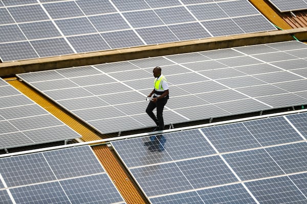 FILE - Mark Munyua, CP solar's technician, examines solar panels on the roof of a company in Nairobi, Kenya, Sept. 1, 2023. (AP Photo/Brian Inganga, File)