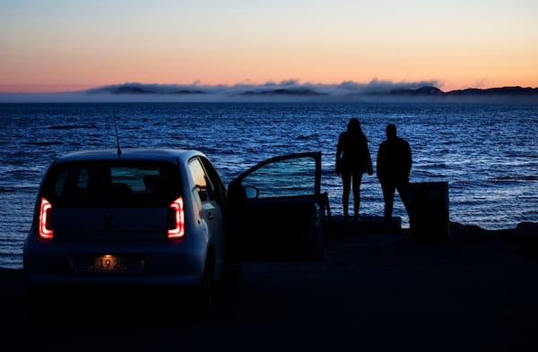 FILE - A couple leave their parked car to look out at the fog hovering off the coast of Nuuk, Greenland, Sunday, July. 30, 2017. (AP Photo/David Goldman, file)