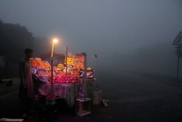 A fruit seller arranges his stall in early morning as smog envelopes the area of Lahore, Pakistan, Thursday, Nov. 14, 2024. (AP Photo/K.M. Chaudary)