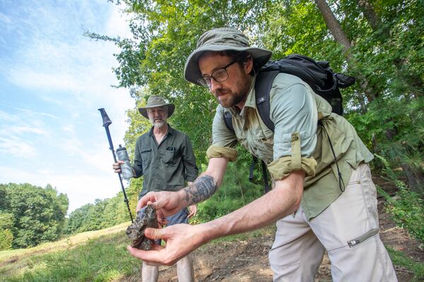 Joe Peery, left, the co-manager of the South River Forest Coalition is with Professional Archeologist Casey Sharp, as he finds a piece of ridge and valley chert, evidence of Native American trade activity in the South River, an area adjacent to the highly contested Atlanta Public Safety Training Center being built on Friday, Sept 1, 2023.  This material is not native to the area and was likely brought to the soapstone quarry to trade.   (Jenni Girtman for The Atlanta Journal-Constitution)