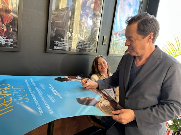 At Tara Theatre for a screening of "Bob Trevino Likes It," Atlanta actor French Stewart signs a poster while his daughter Helene looks on. RODNEY HO/rho@ajc.com