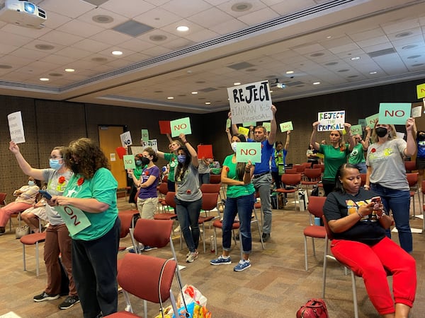 Parents opposed to an Atlanta Public Schools' recommendation to rezone Midtown-area schools hold up signs during a Monday, May 2, 2022, board meeting. VANESSA McCRAY/AJC