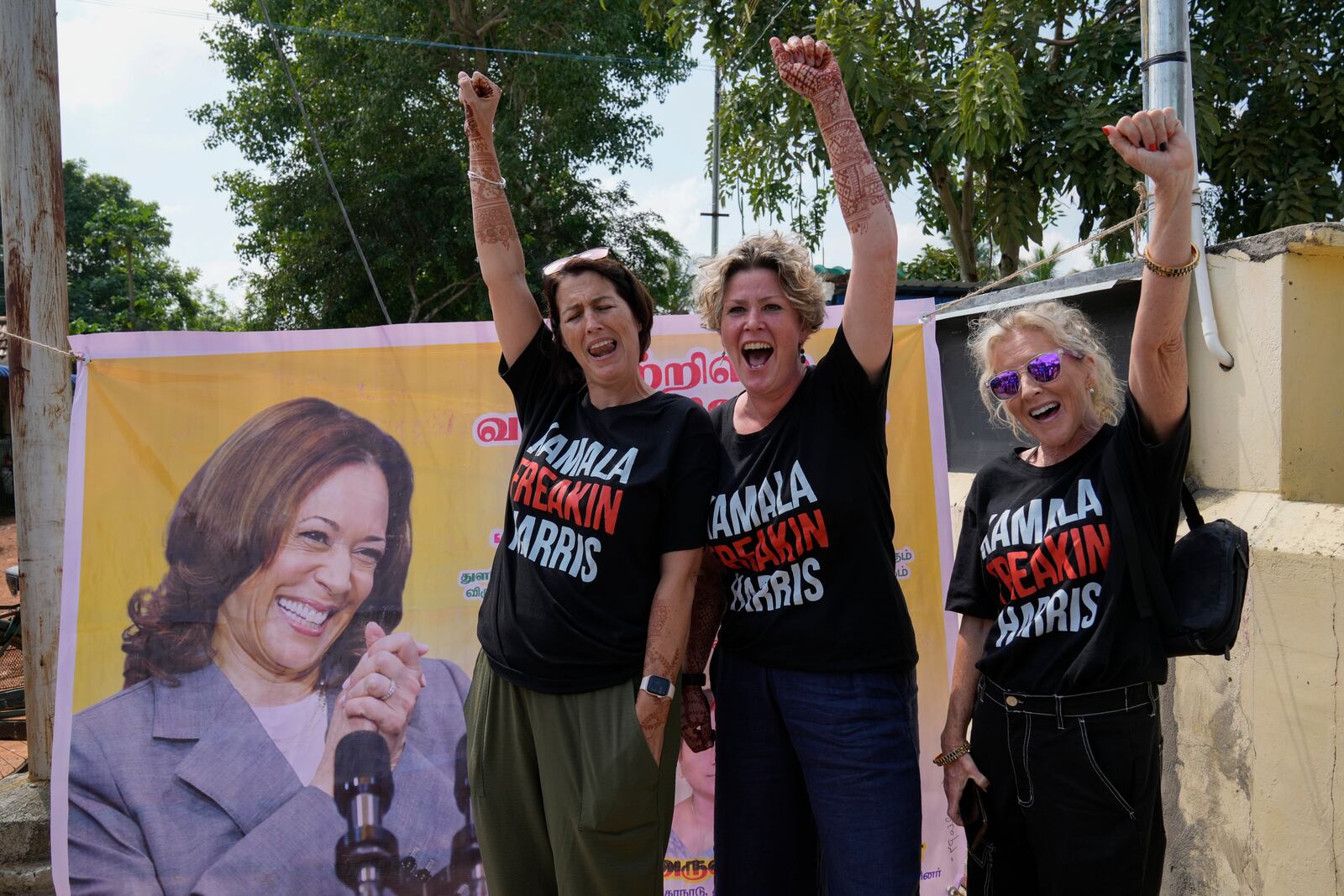 From left, Fiana Jones of United Kingdom, Devony Evans and Sajron Silalenka of United States wearing tees and cheer for Democratic presidential nominee Vice President Kamala Harris outside a temple in Thulasendrapuram, the ancestral village of Harris, in Tamil Nadu state, India, Tuesday, Nov. 5, 2024. (AP Photo/Aijaz Rahi)