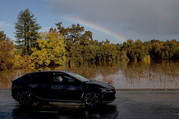 A rainbow is seen as a vehicle drives past a flooded vineyard after a major storm in Forestville, Calif., Saturday, Nov. 23, 2024. (Stephen Lam/San Francisco Chronicle via AP)