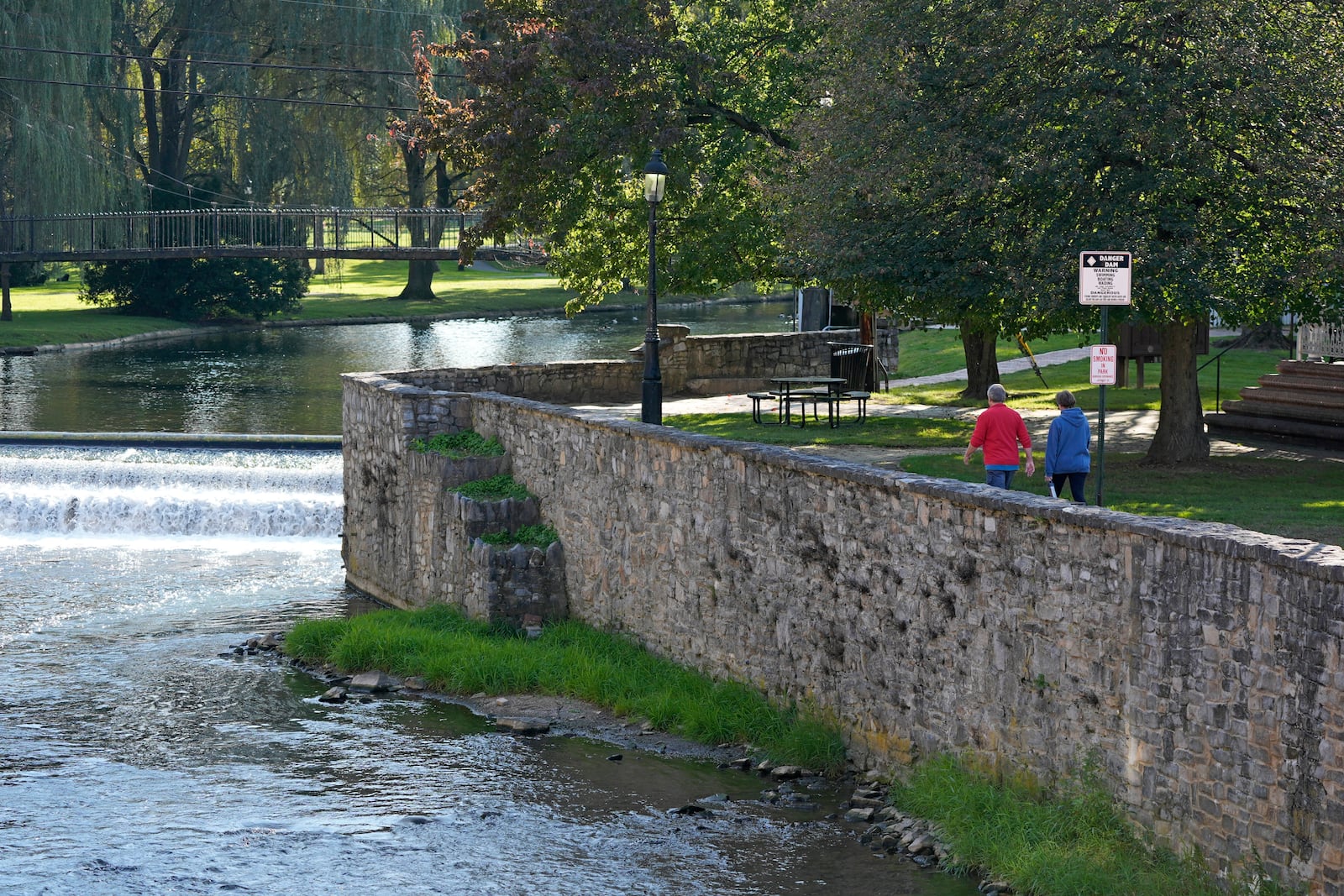 A couple walks in Talleyrand Park in Bellefonte, Pa., Friday, Oct. 18, 2024. (AP Photo/Gene J. Puskar)