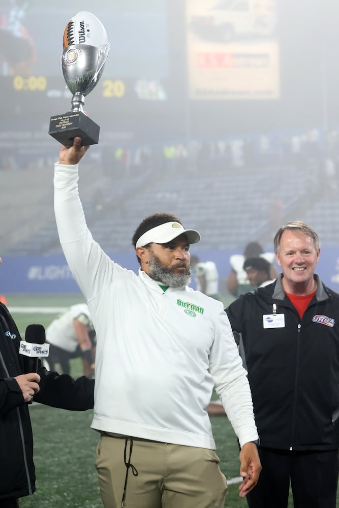 Buford head coach Bryant Appling hoists the trophy after their 21-20 win against Langston Hughes during the Class 6A state title football game at Georgia State Center Parc Stadium Friday, December 10, 2021, Atlanta. JASON GETZ FOR THE ATLANTA JOURNAL-CONSTITUTION