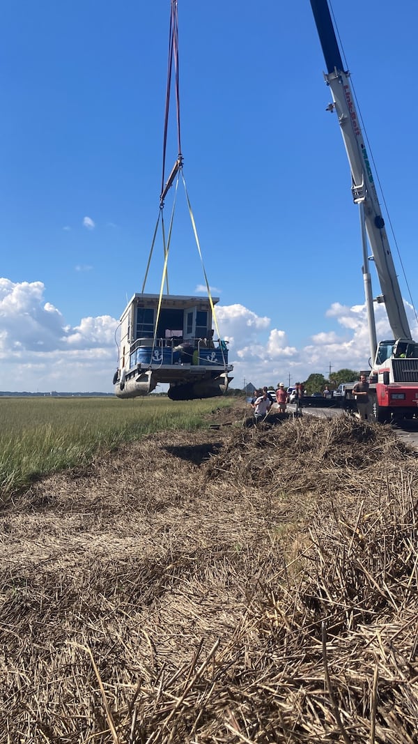 A crane operator removes Castaway from where the boat had run aground during Hurricane Helene. The crane later refloated the vessel at a nearby boat ramp. (Adam Van Brimmer/AJC)