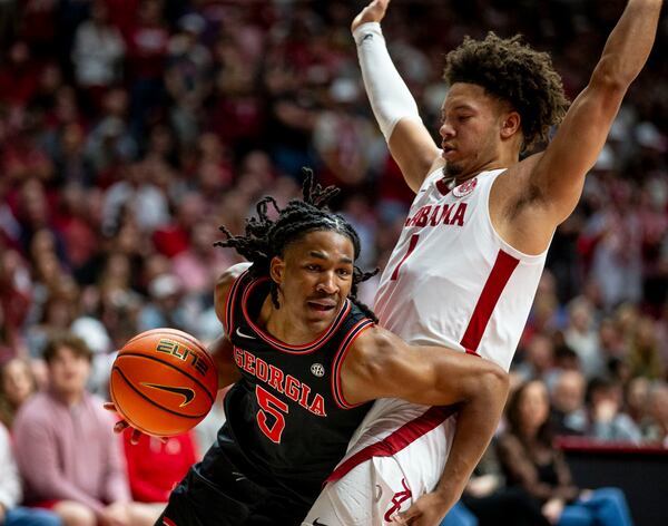 Georgia guard Silas Demary Jr. (5) dribbles past Alabama guard Mark Sears (1) during the first half of an NCAA college basketball game Saturday, Feb. 1, 2025, in Tuscaloosa, Ala. (AP Photo/Laura Chramer)