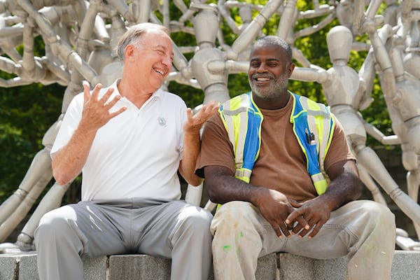 Jack Alexander, in white, enjoys a light moment with his mentee Barron McCoy, in green vest, near McCoy’s work site recently in Atlanta. ELIJAH NOUVELAGE / SPECIAL TO THE AJC