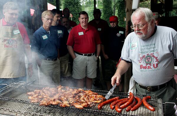 Sam Huff (right) grills some sausage and chicken wings after smoking them during his Lost Mountain Barbecue Company College of Pig Knowledge class a/k/a PorkU. AJC file