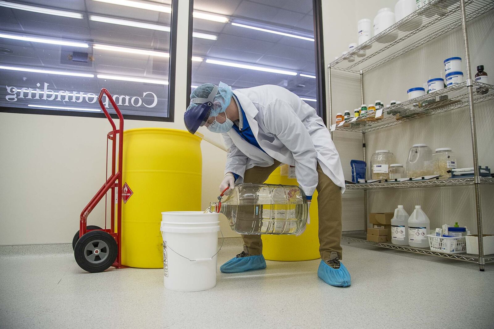 Gage Darby, a technician at the compounding pharmacy Calhoun Drug Company, prepares a mixture of hand sanitizer for healthcare workers in Calhoun on April 8, 2020. The pharmacy is following a mixture approved by the Federal Drug Administration. (ALYSSA POINTER / ALYSSA.POINTER@AJC.COM)