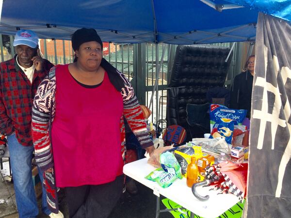 Peoplestown resident Alison Johnson (right) and former state Rep. Douglas Dean stand under a tent during a thunderstorm outside Turner Field on Monday.J. Scott Trubey/strubey@ajc.com