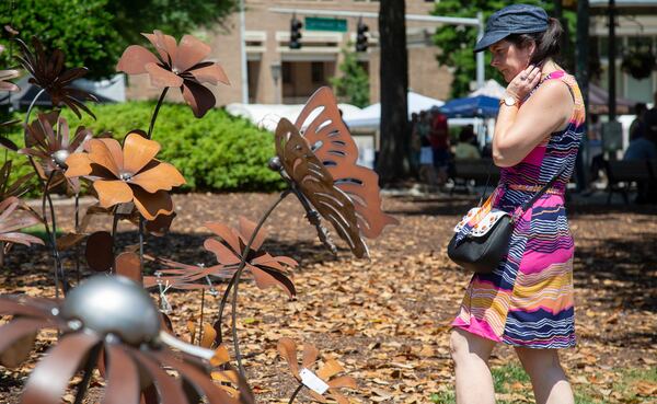 Cindy Smallwood looks over artist William Staubach's garden art sculptures during the annual Decatur Arts Festival on Sunday, May 26, 2019.  STEVE SCHAEFER / SPECIAL TO THE AJC