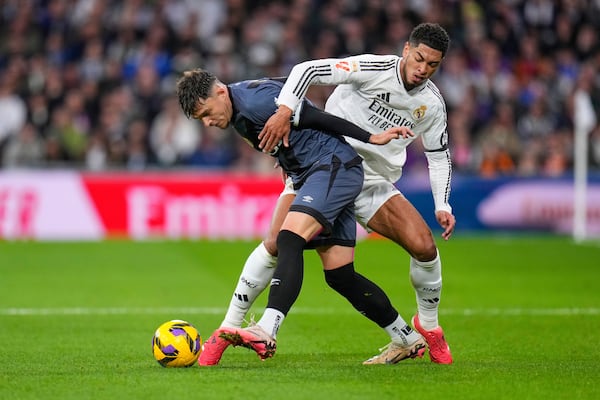 Rayo's Andrei Ratiu, left, challenges for the ball with Real Madrid's Jude Bellingham during the Spanish La Liga soccer match between Real Madrid and Rayo Vallecano at the Santiago Bernabeu stadium in Madrid, Spain, Sunday, March 9, 2025. (AP Photo/Manu Fernandez)