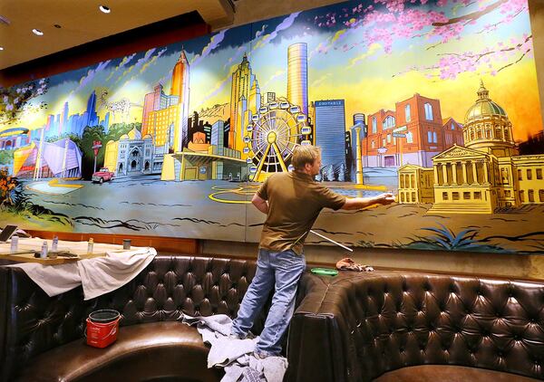 Artist Zack Bird adds some finishing touches to large mural of Atlanta for the famed Palm restaurant under renovation inside the Westin. Photo: Curtis Compton / ccompton@ajc.com