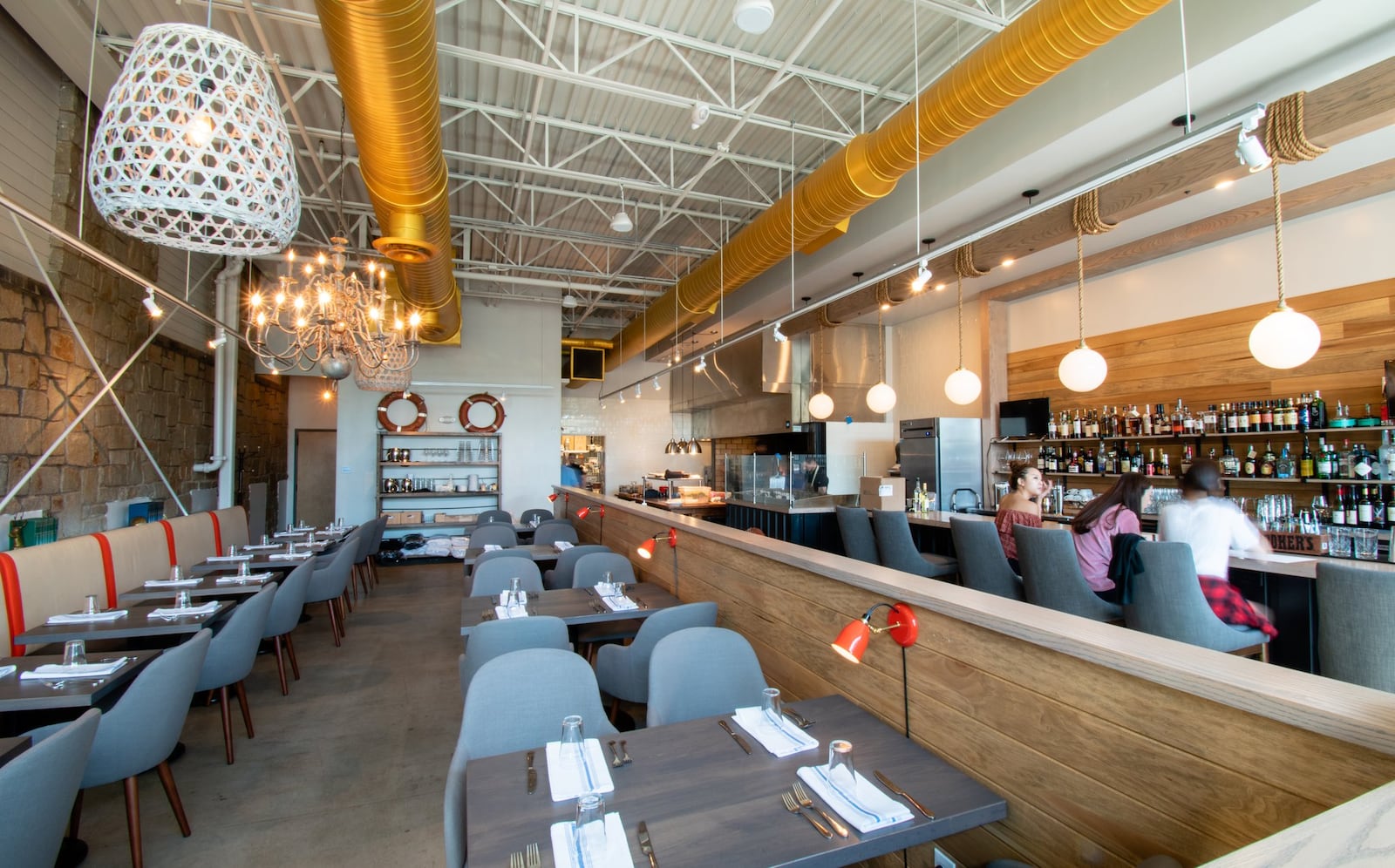 The dining room at Noona Steakhouse & Oyster Bar, where the open-hearth kitchen can be seen in the back right corner. CONTRIBUTED BY HENRI HOLLIS