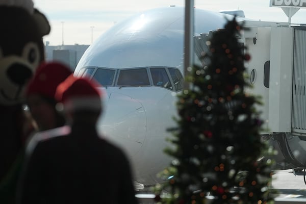 Passengers in holiday garb wait to board an airplane during the United Airlines annual "fantasy flight" to a fictional North Pole at Denver International Airport, Saturday, Dec. 14, 2024, in Denver. (AP Photo/David Zalubowski)