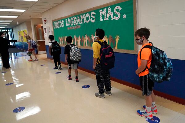 Students keep social distance as they walk to their classroom at Oak Terrace Elementary School in Highwood, Ill., part of the North Shore school district. Nam Y. Huh/ AP Photo