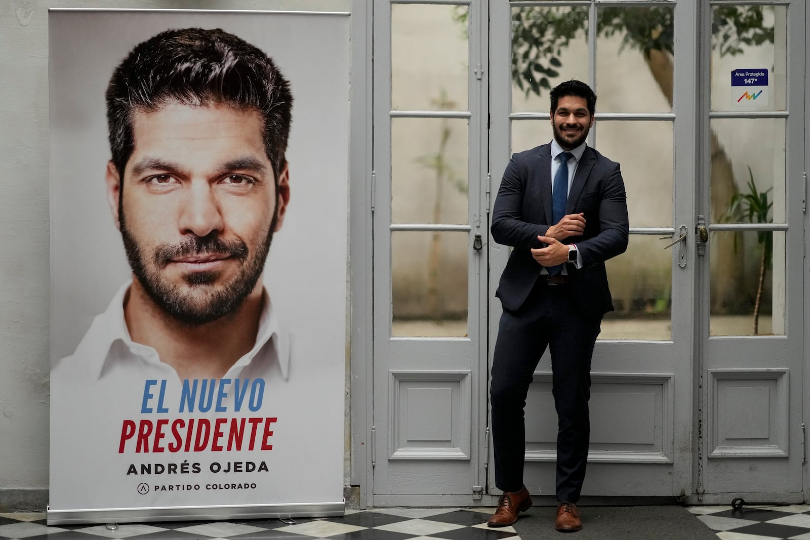 Andres Ojeda, Colorado Party presidential candidate, poses for a photo alongside one of his campaign banners, ahead of Sunday's upcoming general election, in Montevideo, Uruguay, Friday, Oct. 25, 2024. (AP Photo/Natacha Pisarenko)