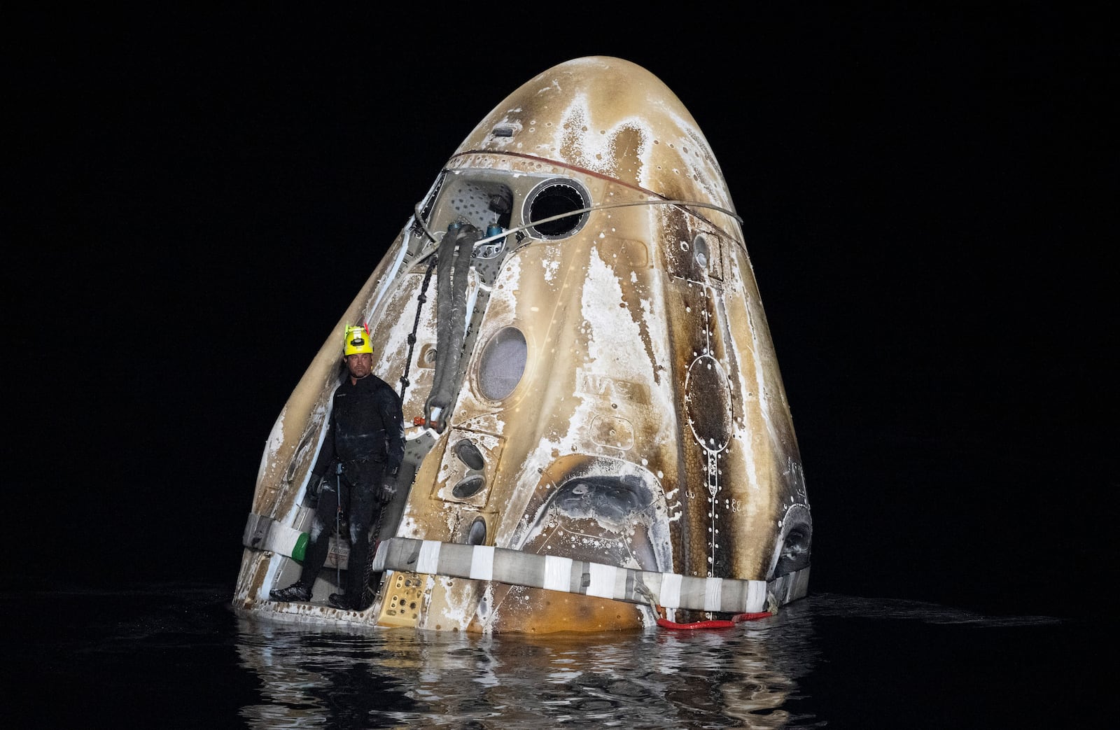 This photo provided by NASA shows a member of the support team as they work around the SpaceX Dragon Endeavour spacecraft shortly after it landed, in the Gulf of Mexico off the coast of Pensacola, Florida, Friday, Oct. 25, 2024. (NASA/Joel Kowsky via AP)