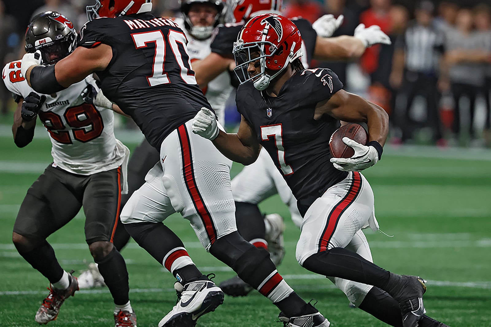 Atlanta Falcons running back Bijan Robinson (7) follows a block by offensive tackle Jake Matthews (70) on Tampa Bay Buccaneers safety Christian Izien (29) during the first half of an NFL football game Thursday, Oct. 3, 2024, in Atlanta. (AP Photo/Butch Dill)