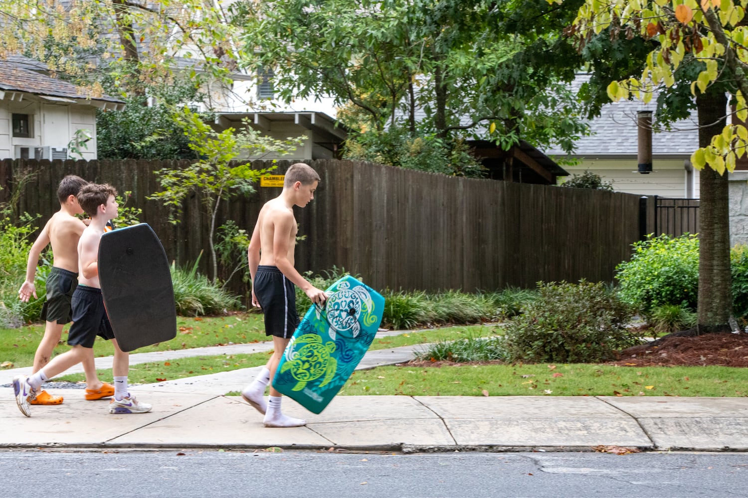 Oakhurst kids out of school today for hurricane Helene, including Henry Bottini, 12, from right, Sean Eingurt, 10 and Charles Bottini, 10, head home for showers after playing in standing water.  “It kinda worked,” Charles said, after trying to boogie board.    (Jenni Girtman for The Atlanta Journal-Constitution)