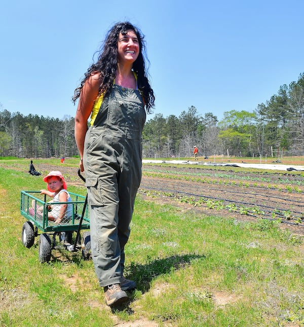 Levity Farms owner Ilana Richards pulls daughter Harlyn along in a plant cart during a tour of the Madison farm. (Chris Hunt for The Atlanta Journal-Constitution)