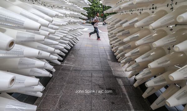 Colbi Ellison makes his way to work past the Midtown Alliance display of "Midtown coneCTOR" on the corner of 15th Street and Peachtree Street. JOHN SPINK / JSPINK@AJC.COM