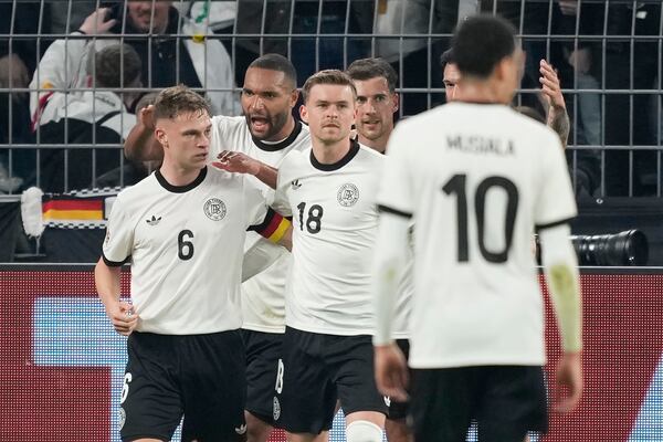 Germany's Joshua Kimmich, left, celebrates with teammates after scoring opening goal during the Nations League quarterfinal second leg soccer match between Germany and Italy at the Signal-Iduna Park in Dortmund, Germany, Sunday, March 23, 2025. (AP Photo/Martin Meissner)