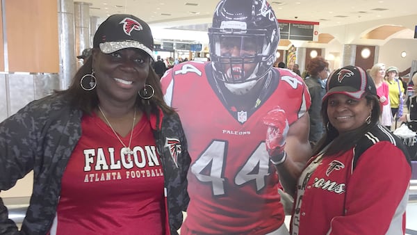 Kimberly Weems, left, and Sandra Weaver pose with a cardboard cutout of Falcons linebacker Vic Beasley at Hartsfield-Jackson International Airport Monday morning. (Richard Halicks / rhalicks@ajc.com)