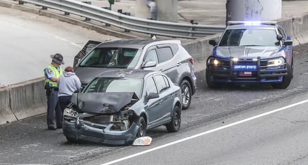 First responders and Georgia Department of Transportation crews work to move several crashed vehicles to the right shoulder of the Downtown Connector early Monday morning.