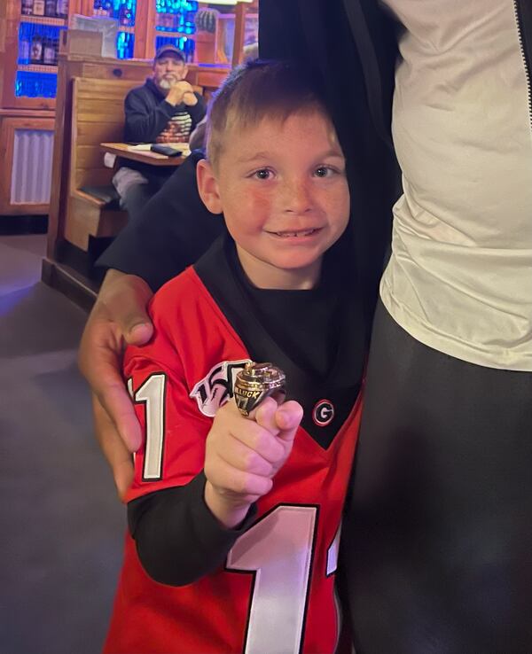 Camdyn Kramer, 7, of White, Ga., shows off Devin Willock's championship ring after meeting the Georgia football player at Texas Roadhouse restaurant in Athens on Saturday. Willock died in a car accident several hours later. (Photo provided to AJC by Sam Kramer)