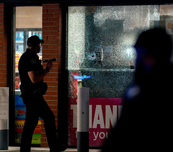 An Atlanta police officer shines his flashlight on a bullet hole in the window a Shell gas station on Northside Drive. Several people were injured in an apparent drive-by shooting on Sunday, July 24, 2022. (Photo: Ben Hendren for The Atlanta Journal-Constitution)