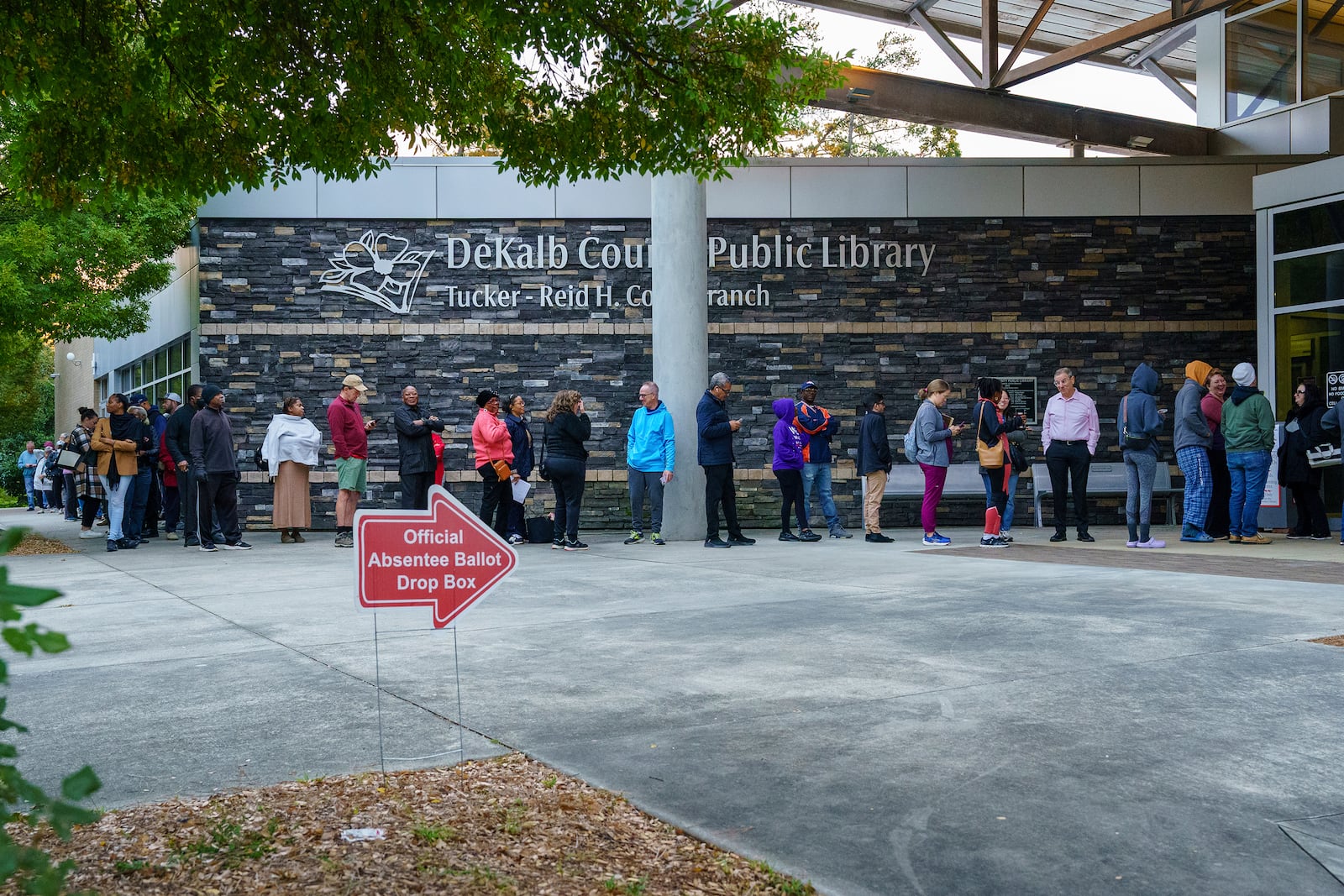 People line up around the building at the Tucker-Reid H. Cofer branch of the Dekalb County Public Library on the first day of early voting, Tuesday, Oct. 15, 2024 in Tucker, Ga. (Matthew Pearson/WABE via AP)