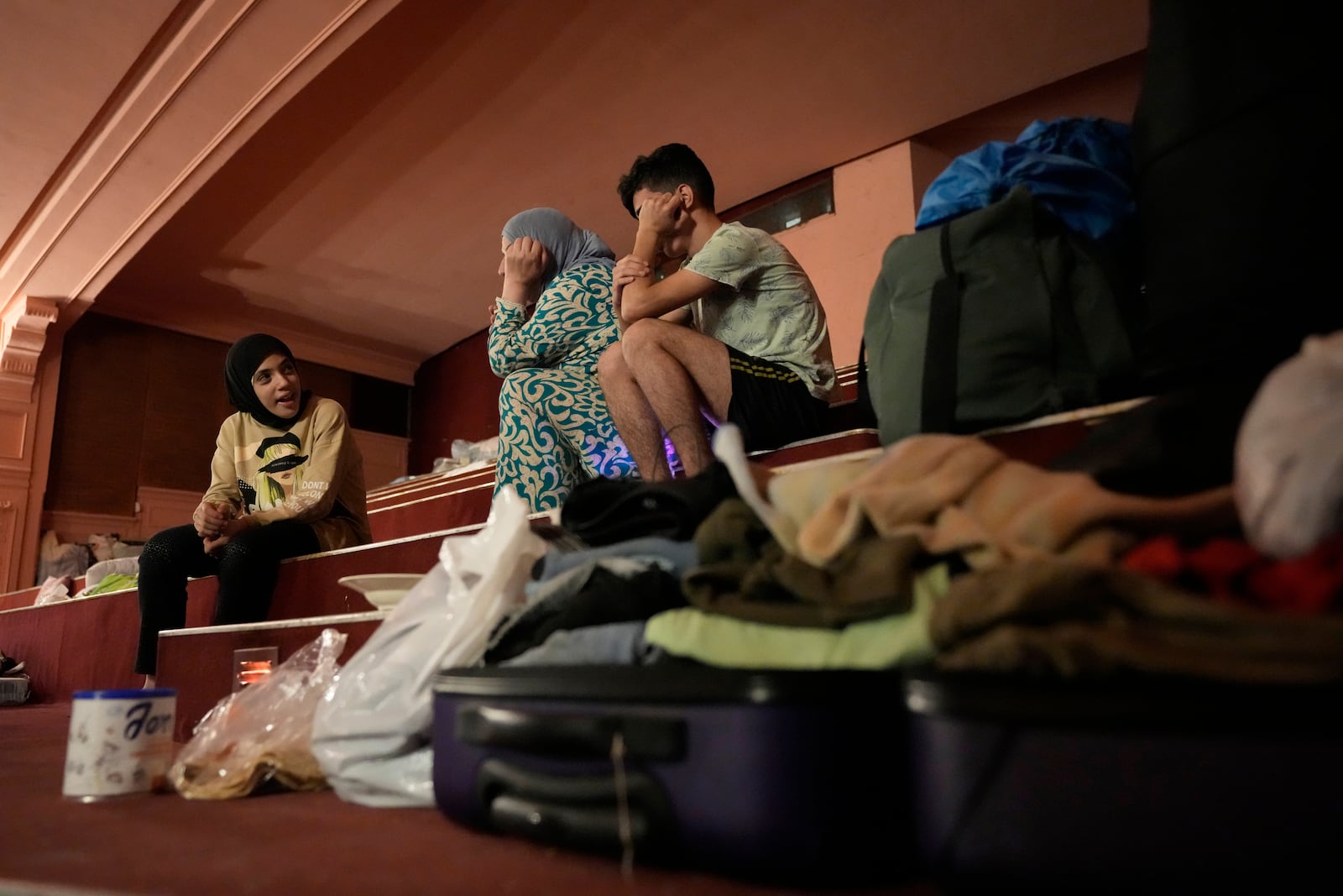 Mona Hanafi, center, who fled the ongoing Hezbollah-Israel war in south Lebanon, sits with her family, inside one of Beirut's oldest and best known movie theatres, Le Colisee, in Beirut, Lebanon, Tuesday, Oct. 22, 2024. (AP Photo/Hussein Malla)