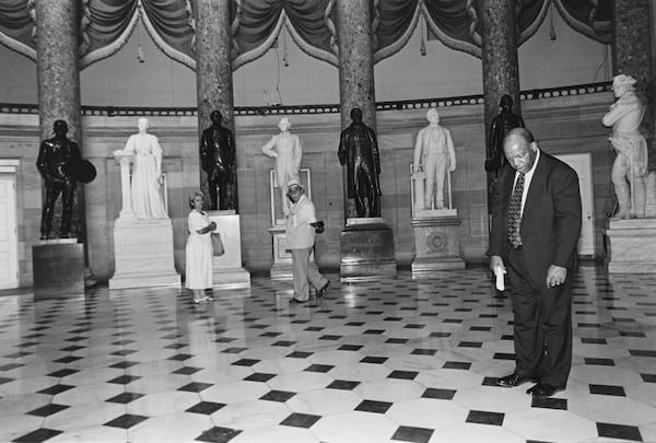 Representative John Lewis, D-Ga., giving a Capitol tour to a constituent demonstrates how the "sound system" works. Between 2 spots about 20 feet apart in Statuary Hall you can whisper in one and be distinctly heard in the other. July 22, 1993 (Photo by Maureen Keating/CQ Roll Call via AP Images)