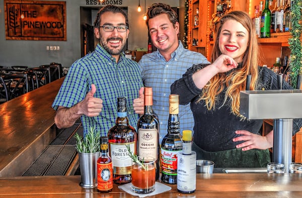 Bartenders Martín Aramayo (from left) and Zachary Williams and bar manager Kasey Emmett stand behind their collaborative drink, Rosemary’s Baby, featured at the Pinewood in downtown Decatur. STYLING BY KASEY EMMETT / CONTRIBUTED BY CHRIS HUNT PHOTOGRAPHY