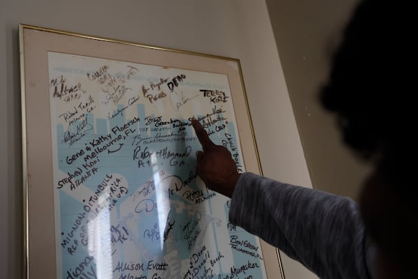 Sally Mae Hollis points to a poster with signatures of people, including former President Jimmy Carter. They gave it to her as a gift during their visit in 1988 to help build her back deck as part of his work project with Habitat for Humanity. (Miguel Martinez/AJC)