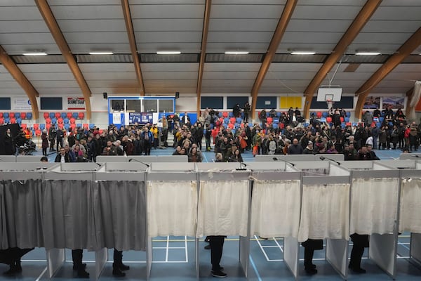 People line up in the back ground to cast their vote in parliamentary elections, in Nuuk, Greenland, Tuesday, March 11, 2025. (AP Photo/Evgeniy Maloletka)