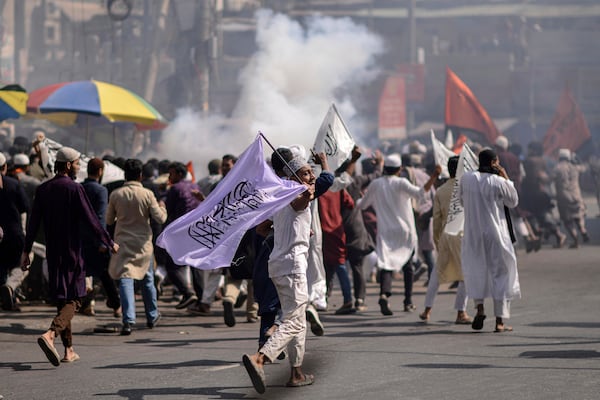 Members and supporters of the banned Islamist group Hizbut Tahrir run after police used teargas near Baitul Mokarram Mosque in Dhaka, Bangladesh, Friday, March 7, 2025. (AP Photo/Mahmud Hossain Opu)