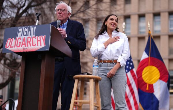 Sen. Bernie Sanders, I-Vt., left, speaks as Rep. Alexandria Ocasio-Cortez, D-N.Y., responds to calls of support during a stop of their "Fighting Oligarchy" tour that filled Civic Center Park, Friday, March 21, 2025, in Denver. (AP Photo/David Zalubowski)