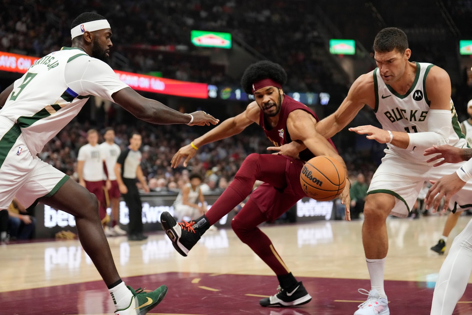 Cleveland Cavaliers center Jarrett Allen, center, reaches for the ball with Milwaukee Bucks forward Bobby Portis Jr., left, and center Brook Lopez, right, in the first half of an NBA basketball game, Monday, Nov. 4, 2024, in Cleveland. (AP Photo/Sue Ogrocki)