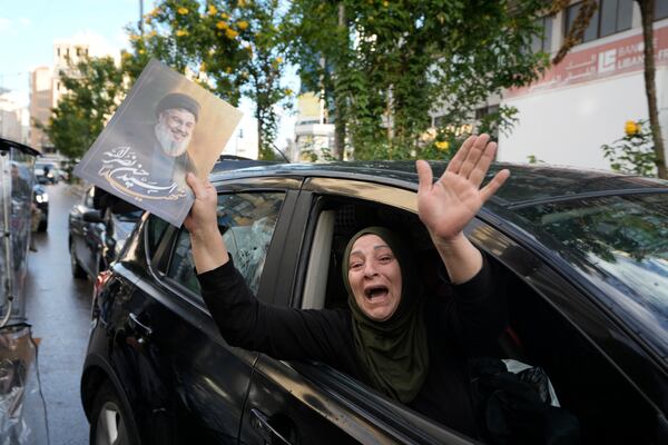 A woman carries a picture of slain Hezbollah leader Hassan Nasrallah as she returns to Dahiyeh, in Beirut, Lebanon, following a ceasefire between Israel and Hezbollah, Wednesday, Nov. 27, 2024. (AP Photo/Bilal Hussein)