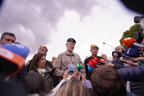 Spain's King Felipe VI speaks with journalists after a visit to a military base with Spain's Defense Minister Margarita Robles, centre left, on the outskirts of Valencia after floods left hundreds dead or missing in the Valencia region in Spain, Tuesday, Nov. 12, 2024. (AP Photo/Alberto Saiz)