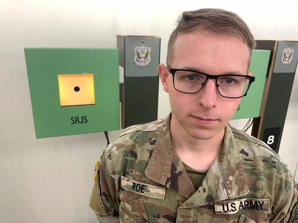 Sgt. Ivan Roe holds up a quarter to show the size of the target in the 10 meter air rifle event. The black dot shown encompasses scoring rings four through 10 in this event. (Photo Courtesy of Kelby Hutchison)