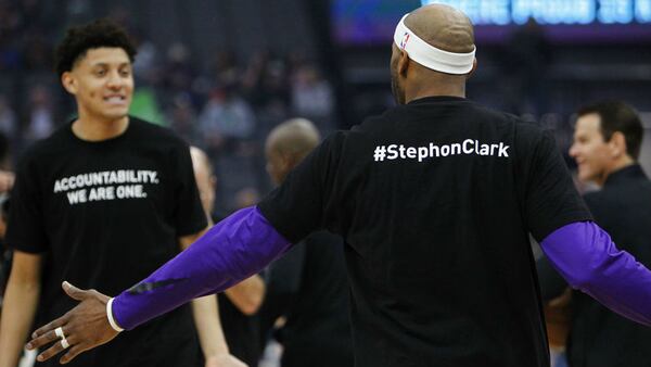 Sacramento Kings players Vince Carter, right, and Justin Jackson, along with their teammates and Boston Celtics players, wear T-shirts in memory of Stephon Clark before the start of an NBA basketball game against the Celtics in Sacramento, Calif., Sunday, March 25, 2018. Clark, 22, died March 18 after two officers fired 20 rounds at him as he stood, unarmed, on the back patio of his grandparents' home. His death has sparked protests across Sacramento and beyond.