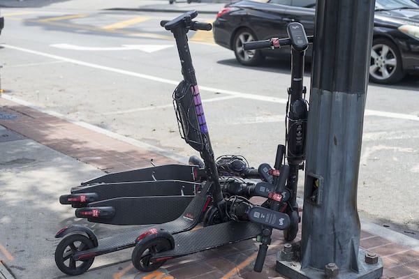 Electric scooters sit piled up on the sidewalk near Centennial Olympic Park.