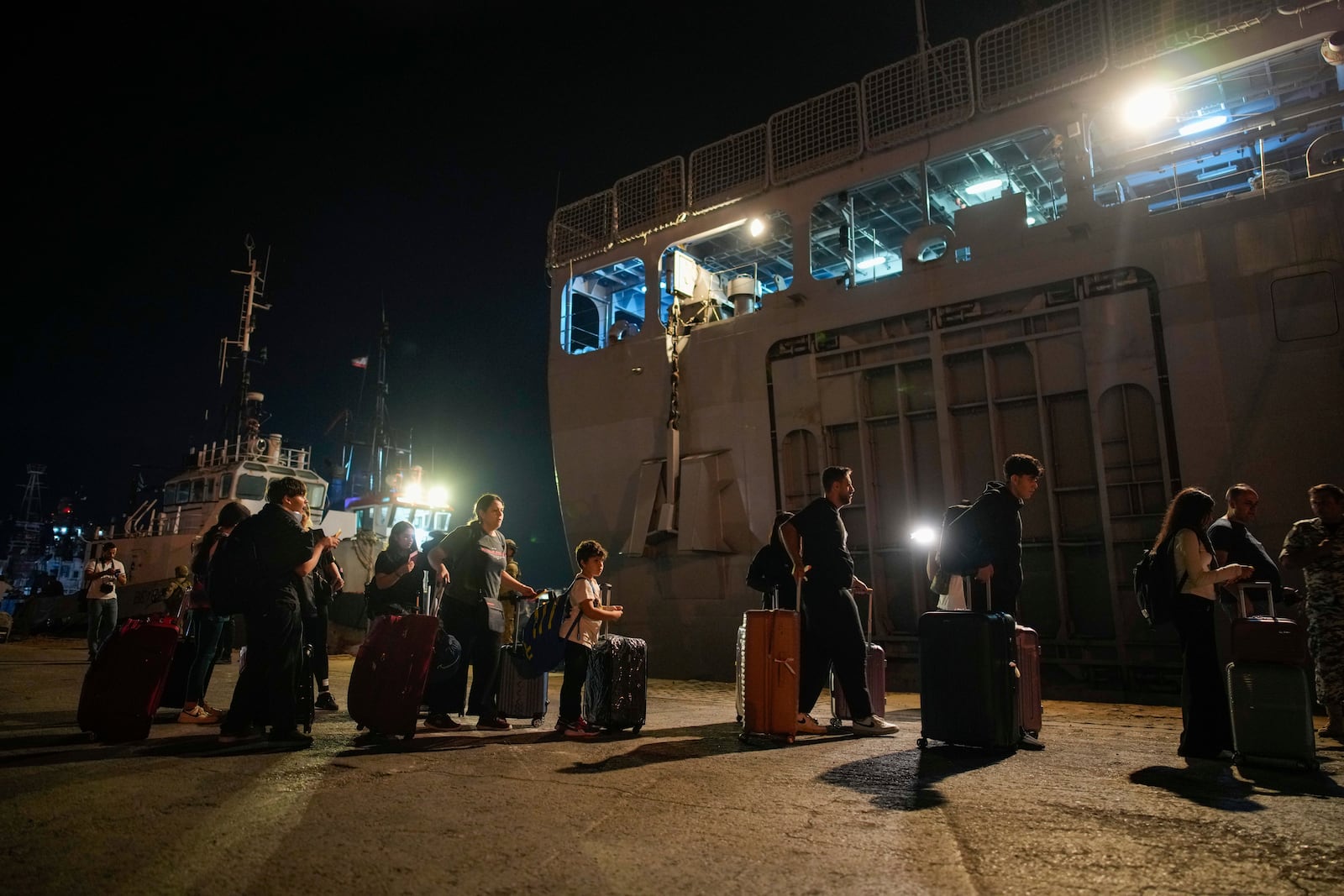 Turkish citizens walk to board Turkish military ships to evacuate them from Lebanon to Turkey, in Beirut port on Wednesday, Oct. 9, 2024. (AP Photo/Emrah Gurel)