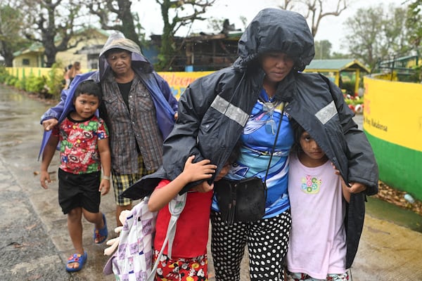 Residents use jackets to protect them from rain as they evacuate their homes in Santa Ana, Cagayan province, northern Philippines as Typhoon Usagi approaches Thursday, Nov. 14, 2024. (AP Photo/Noel Celis)